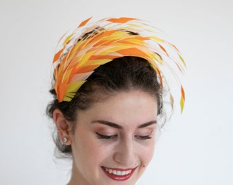 Chapeau fascinateur en plumes jaunes, oranges, roses et blanches. Un casque glamour à porter lors de vos occasions spéciales.
