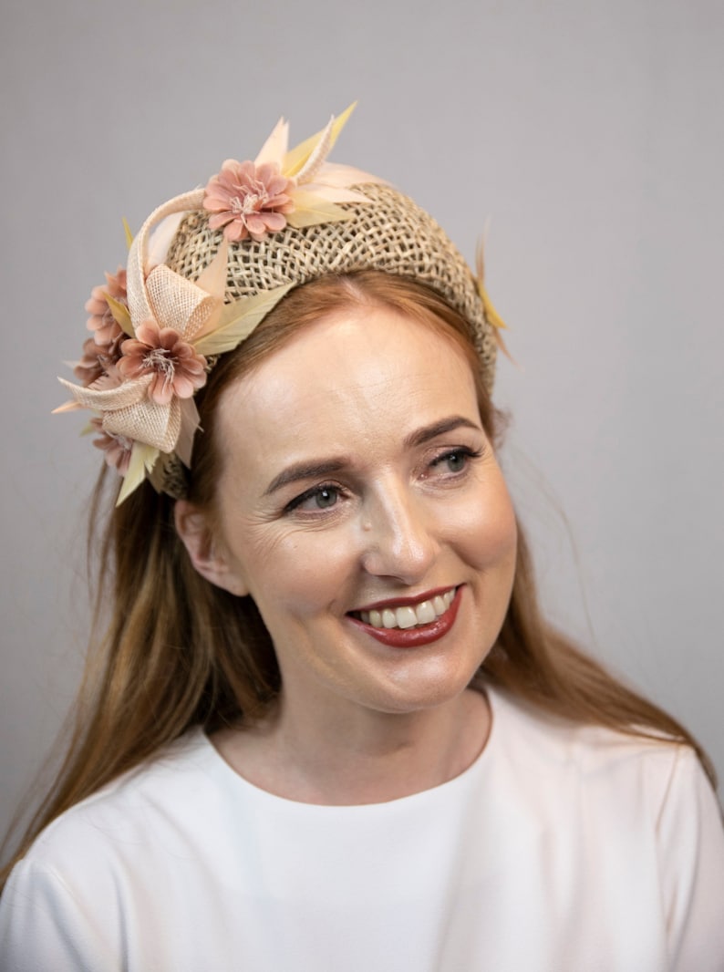 May include: A woman with long, brown hair is wearing a headband made of woven straw with pink fabric flowers and leaves.