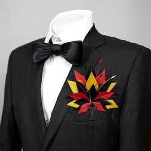 Fazzoletto da taschino con piume nei colori della bandiera tedesca. Accessorio per abito patriottico. Taschino di colore nero, rosso e giallo.