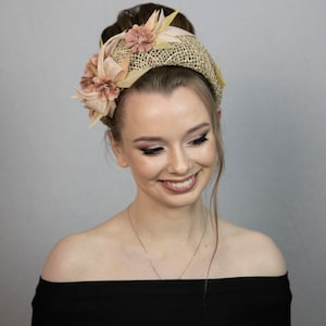 May include: A woman wearing a black off-the-shoulder dress with a straw headband adorned with pink and yellow flowers.