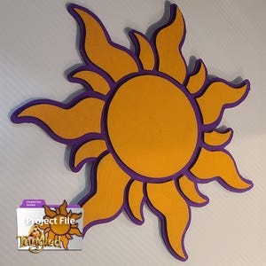 Peut inclure: Décoration en bois en forme de soleil aux tons jaune et violet. Le soleil a un centre circulaire et des rayons stylisés. L'image comprend une icône de fichier numérique avec le texte "Project File" et le mot "Tangled".