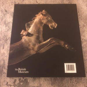 May include: The back cover of a book titled "The British Museum". The cover features a photograph of a bronze horse sculpture. The book's ISBN number is printed on the back cover.