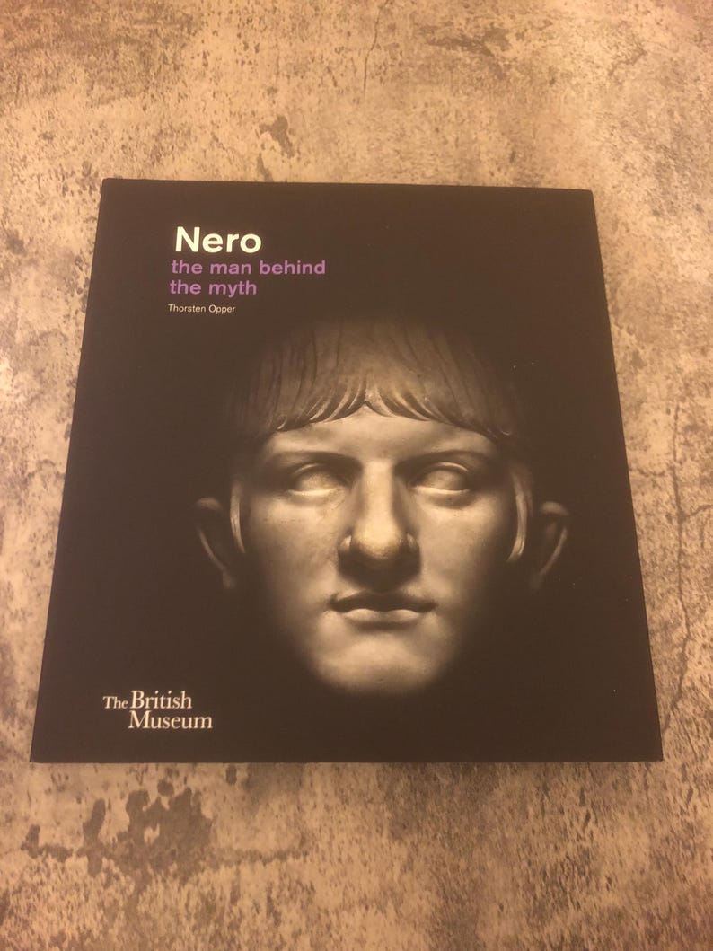 May include: A black book with the title "Nero the man behind the myth" by Thorsten Opper. The book cover features a black and white image of a bust of Nero. The book is published by The British Museum.