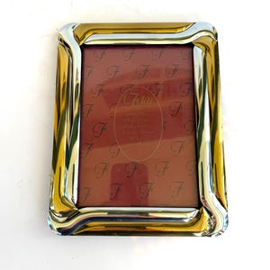 May include: A white ceramic mug with a black handle and the text "But First, Coffee" in a bold, black font. The mug is set against a neutral background, highlighting its simple design.