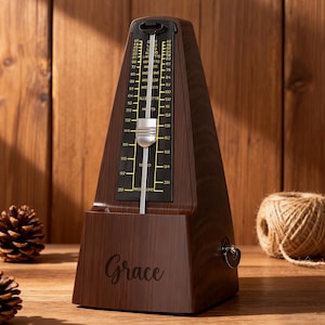 May include: A brown wooden metronome with a black face displaying tempo markings. The word "Grace" is inscribed on the base. A silver pendulum swings in front of the tempo scale. A key is visible on the side.
