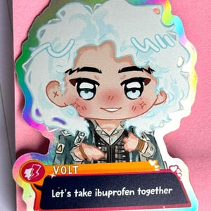 Puede incluir: Una pegatina holográfica con un personaje de dibujos animados con pelo azul claro y una chaqueta de estilo militar. La pegatina incluye el texto "VOLT" y "Let's take ibuprofen together" en un bocadillo.