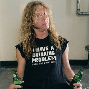 May include: A black sleeveless t-shirt with the text "I HAVE A DRINKING PROBLEM" and the quote "I HAVE 2 HANDS & ONLY 1 MOUTH". The person is holding two green glass bottles.