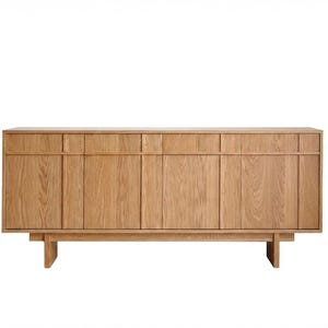 May include: A light-colored wooden sideboard with multiple doors and drawers. The cabinet has a rectangular shape and is supported by two legs. The doors and drawers have vertical wood grain patterns. The sideboard is a piece of furniture.