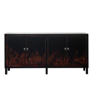 May include: A long rectangular sideboard cabinet featuring four doors with circular metal ring pulls. The piece has a distressed black finish that reveals warm reddish-brown wood tones underneath, supported by short, straight, block-style legs.
