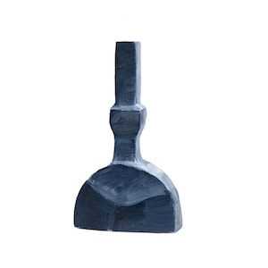 May include: A dark blue, abstract sculpture with a geometric base and a vertical, rectangular top. The artwork has a hand-painted appearance, with visible brushstrokes and a matte finish. The sculpture is set against a plain white background.