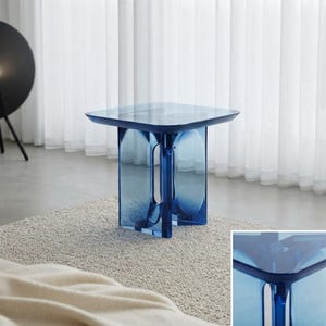 May include: A square side table constructed from translucent blue acrylic material. The table features a flat top surface supported by a central base with four curved, open-arched legs that create a hollow, geometric silhouette with a glossy finish.