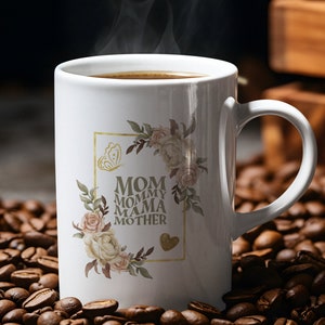 May include: White ceramic coffee mug with a floral design and the text "MOM MOMMY MAMA MOTHER" in a gold frame. The mug is filled with coffee and steam is rising from the top. The mug is sitting on a bed of coffee beans.