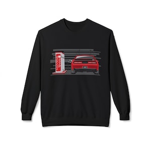 May include: Black sweatshirt with a graphic of a red car at a petrol station. The car is depicted from the rear, next to a vintage-style petrol pump. The background has horizontal grey lines.