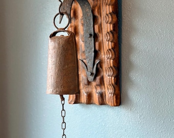 Campana de pared antigua de hierro forjado a mano con percutor sobre placa de madera tallada / Decoración arquitectónica europea de salvamento
