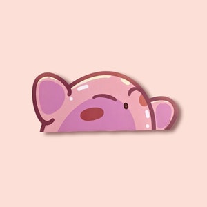 Puede incluir: Un cerdo de dibujos animados rosa, mirando por encima del borde, con un ojo gui&ntilde;ado y una mejilla sonrojada. El cerdo tiene orejas grandes y un hocico redondeado. El fondo es de color rosa claro.
