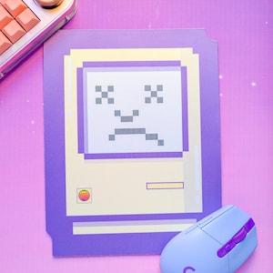 May include: A purple and yellow pixelated design featuring a sad face, a light blue computer mouse with purple accents, and a keyboard. The design is on a pink and purple background.