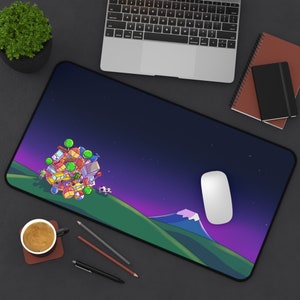 Puede incluir: Alfombrilla de ratón rectangular con un diseño de paisaje de dibujos animados colorido. El diseño presenta una colina con un grupo de objetos, una vaca y una montaña contra un cielo estrellado púrpura y azul. Un ratón blanco está encima.