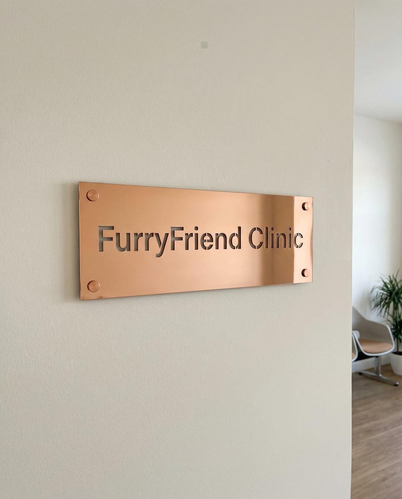 K&ouml;nnte beinhalten: Ein rechteckiges, kupferfarbenes Schild mit den ausgeschnittenen Worten "FurryFriend Clinic". Das Schild ist mit vier sichtbaren Schrauben an einer hellen Wand befestigt. Das Schild befindet sich in einem hellen Raum.