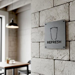 K&ouml;nnte beinhalten: Ein rechteckiges Metallschild mit dem Wort "REFRESH" in fetter Schrift. Oberhalb des Wortes befindet sich eine Grafik eines Glases. Das Schild ist an einer hellfarbigen Backsteinmauer angebracht.
