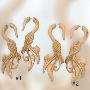 Op de afbeelding: Vier lichtbeige, gesneden houten oorbellen. Elke oorbel heeft een gebogen haakvorm met een gedetailleerd blad- en wijnstokontwerp. De oorbellen zijn genummerd #1 en #2.