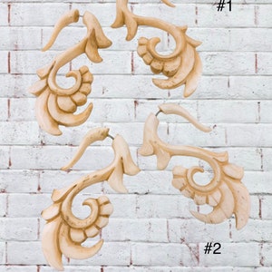 Op de afbeelding: Twee paar oorstekers van gegraveerd, ivoorwit hout. De oorstekers zijn gevormd als een gestileerd bloemmotief met een gebogen haak. De oorstekers zijn gemarkeerd met #1 en #2.