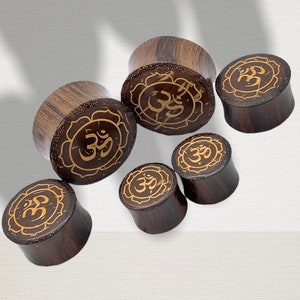 May include: Six wooden ear gauges with a brown finish and gold Om symbol designs.