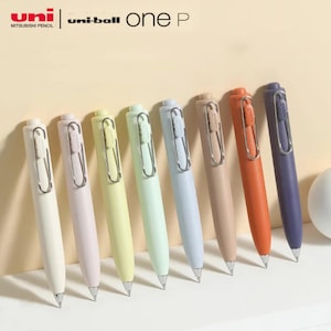 May include: A set of ten pastel-coloured pens with silver clips and black ink. The pens are arranged in a row on a white surface. The brand name "uni-ball one P" is visible at the top of the image.