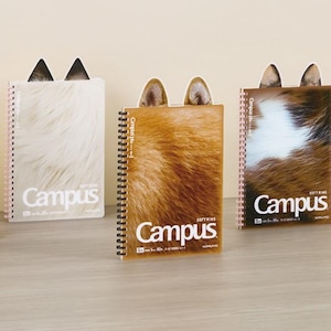 May include: Five spiral bound notebooks with faux fur covers. Each notebook has a pair of cat ears on the front. The notebooks are all different colors and patterns. The notebooks are labeled "Campus" on the front.