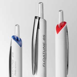 May include: Close-up of three white Pentel FLOATUNE 05 pens. The pens have silver accents and clear tips. One pen has a blue accent, one has a red accent, and one has a silver accent. The text "FLOATUNE 05" is printed on the pens.
