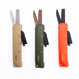 Może przedstawiać: Trzy wielofunkcyjne noże w kolorze beżowym, oliwkowym i pomarańczowym. Każdy ma ostrze, nożyczki i nóż do cięcia. Tekst "HARD-AKE" jest wydrukowany z boku każdego narzędzia wraz z etykietami funkcji.