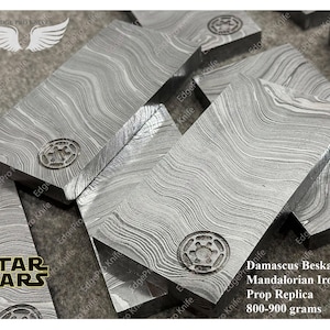 May include: A close-up of a Damascus Beskar Ingot, a prop replica of the Mandalorian Iron, weighing 800-900 grams. The ingot is made of a patterned metal with a swirling design.