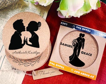 May include: Cork coasters with black silhouettes of a kissing couple and a bride and groom. The coasters are round and have the names "Arthur & Kaitlyn" and "Samuel & Grace" printed on them. A small tag reads "Thank you."