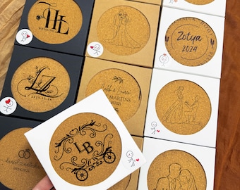May include: A collection of 10 round cork coasters with personalized wedding designs. Each coaster features a unique design with initials, dates, and names. The coasters are in various colors, including black, white, and brown.