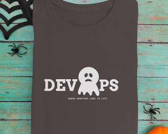 Könnte beinhalten: Dunkelgraues T-Shirt mit Rundhalsausschnitt, dem Wort "DEVOPS" und einer weißen Geistergrafik. Der Text "WHERE MONSTERS COME TO LIFE" steht darunter. Halloween-Kleidung.