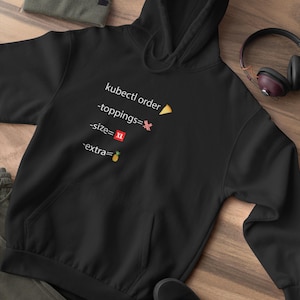 Op de afbeelding: Zwarte hoodie met een witte afbeelding waarop "kubectl order" staat met emoji's voor pizza, bacon, maat XL en ananas.