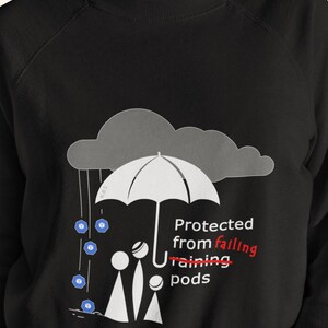 Może przedstawiać: Czarna bluza z nadrukiem osoby stojącej pod parasolem z tekstem "Protected from failing raining pods".