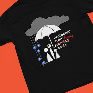 May include: Black t-shirt with a graphic of two people standing under an umbrella, with blue raindrops falling from a gray cloud. The text "Protected from falling raining pods" is written on the shirt.