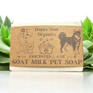 Puede incluir: Una pastilla de jabón para mascotas de leche de cabra sin perfume con una etiqueta de papel marrón. La etiqueta presenta ilustraciones de perros, burbujas y el texto "Happy Soul Organics" y "Goat Milk Pet Soap". El jabón pesa 113 gramos.