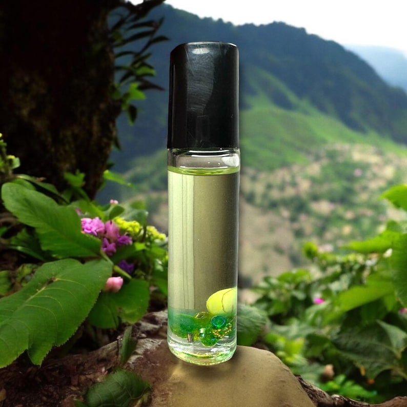 Pu&ograve; includere: Un flacone roll-on in vetro trasparente con tappo nero contenente un liquido giallo chiaro. Alla base del flacone, piccole perline verdi e una singola perla gialla sono immerse nel liquido, visibili attraverso il vetro trasparente.