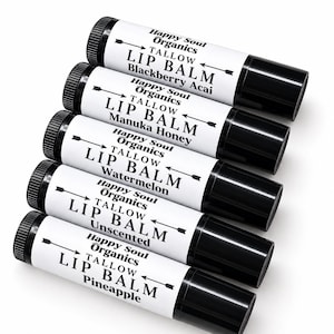 May include: Five cylindrical black plastic lip balm tubes with white labels. Each label features the text Happy Soul Organics, Tallow Lip Balm, and a specific flavour: Blackberry Acai, Manuka Honey, Watermelon, Unscented, and Pineapple.