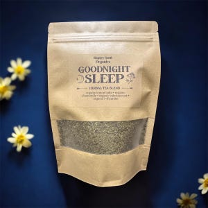 May include: A brown paper bag of "Goodnight Sleep" herbal tea blend. The bag has a clear window showing the tea leaves. The label includes the text "Happy Soul Organics" and lists ingredients like lemon balm and chamomile. Yellow flowers are scattered around the bag.