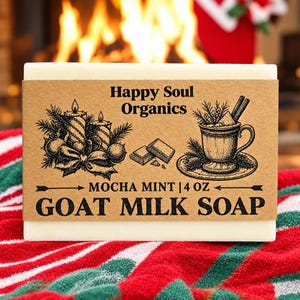 Puede incluir: Una pastilla rectangular de jabón de leche de cabra en color blanco roto envuelta en una etiqueta de papel marrón. La etiqueta muestra el texto Happy Soul Organics, Mocha Mint y 4 oz, junto a ilustraciones en tinta negra de velas y una taza.