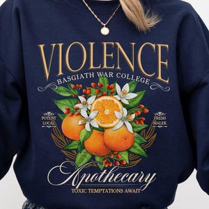 a woman sitting on the ground wearing a sweatshirt with a picture of an orange on
