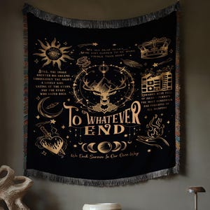 Könnte beinhalten: Schwarzer Wandteppich mit goldenen Himmels- und mystischen Designs, darunter Sonne, Mond, Hirsch und Text "To Whatever End". Der Wandteppich ist gefranst und hängt über einer Holzkonsolentisch.