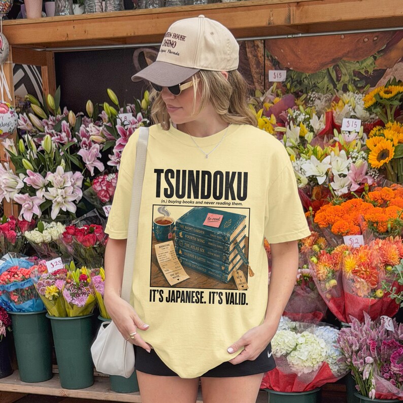 Yellow t-shirt with "TSUNDOKU" text and stack of books.