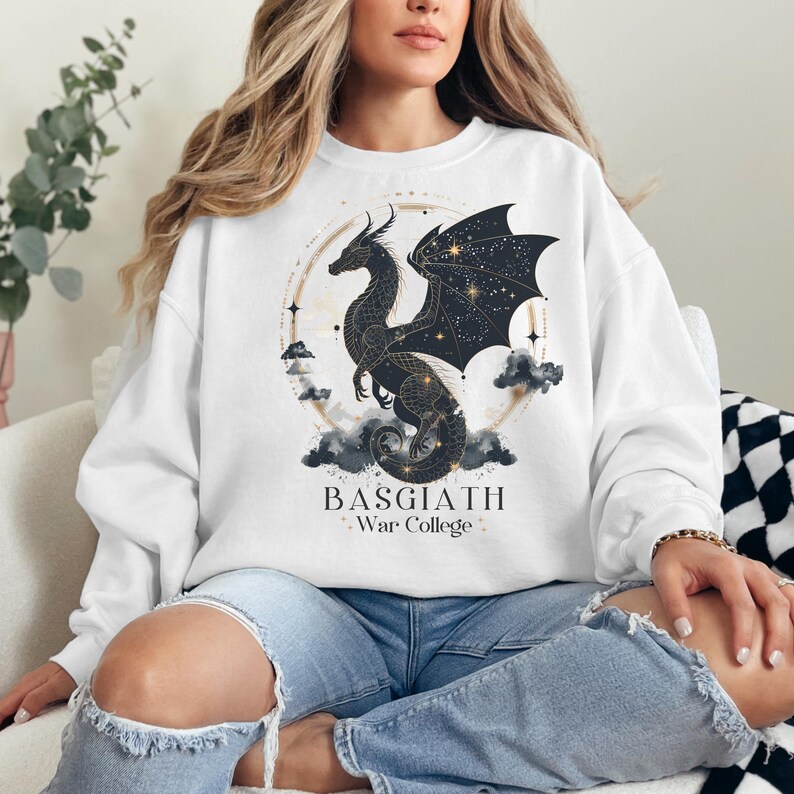 a woman sitting on a couch wearing a white sweatshirt with a black dragon on it