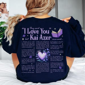 a woman sitting on a bed wearing a t - shirt that says i love you