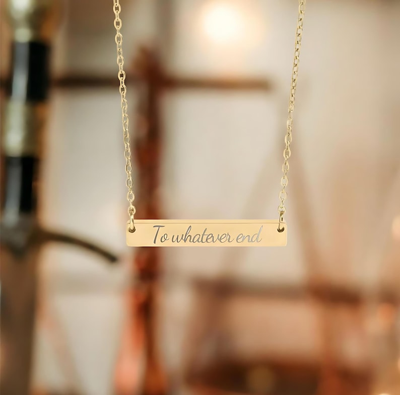 A gold-colored necklace with a rectangular pendant that says "To whatever end".