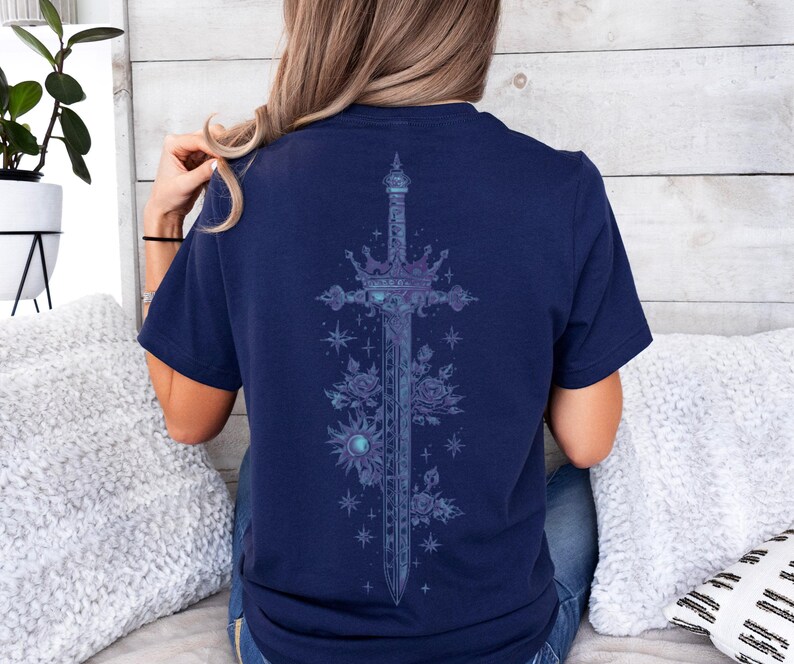 a woman sitting on a bed wearing a t - shirt with a cross on it