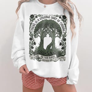 White sweatshirt with "The Twin Alders" art and quote.